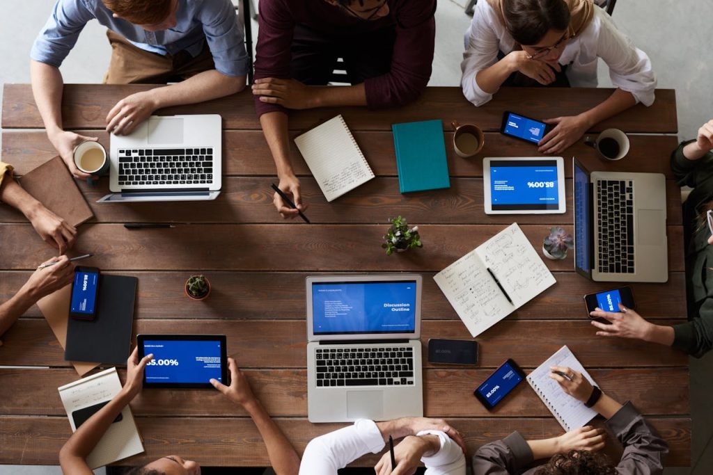 pexels-photo-3183150 Overhead view of a diverse team in a business meeting using laptops and tablets.